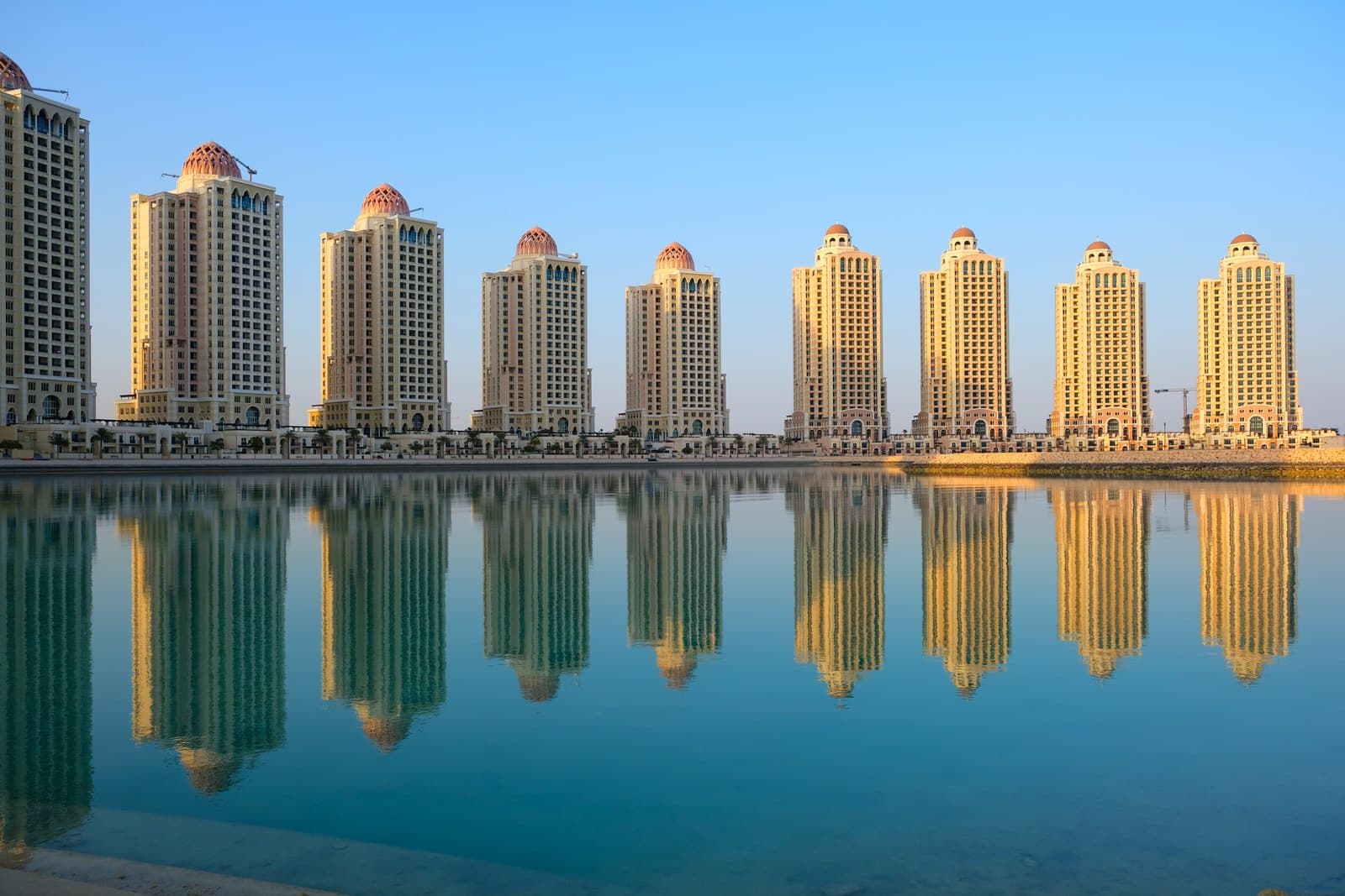 Residential towers with domed rooftops reflected in the water at The Pearl Island, Doha